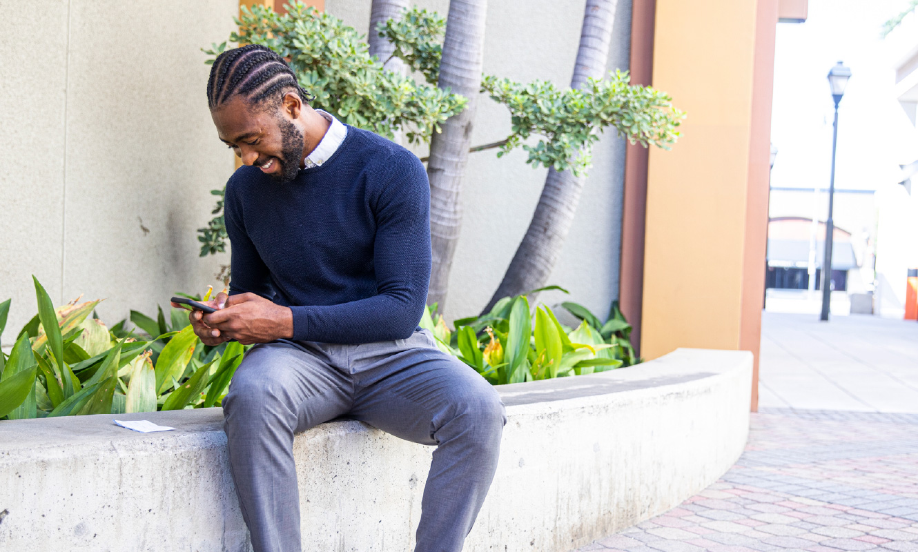 Man outside taking a picture of a paper check with his smartphone.